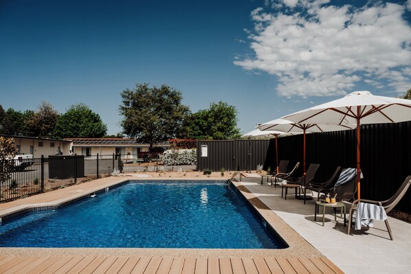 Alberca al aire libre, sombrillas en la alberca y camastros 