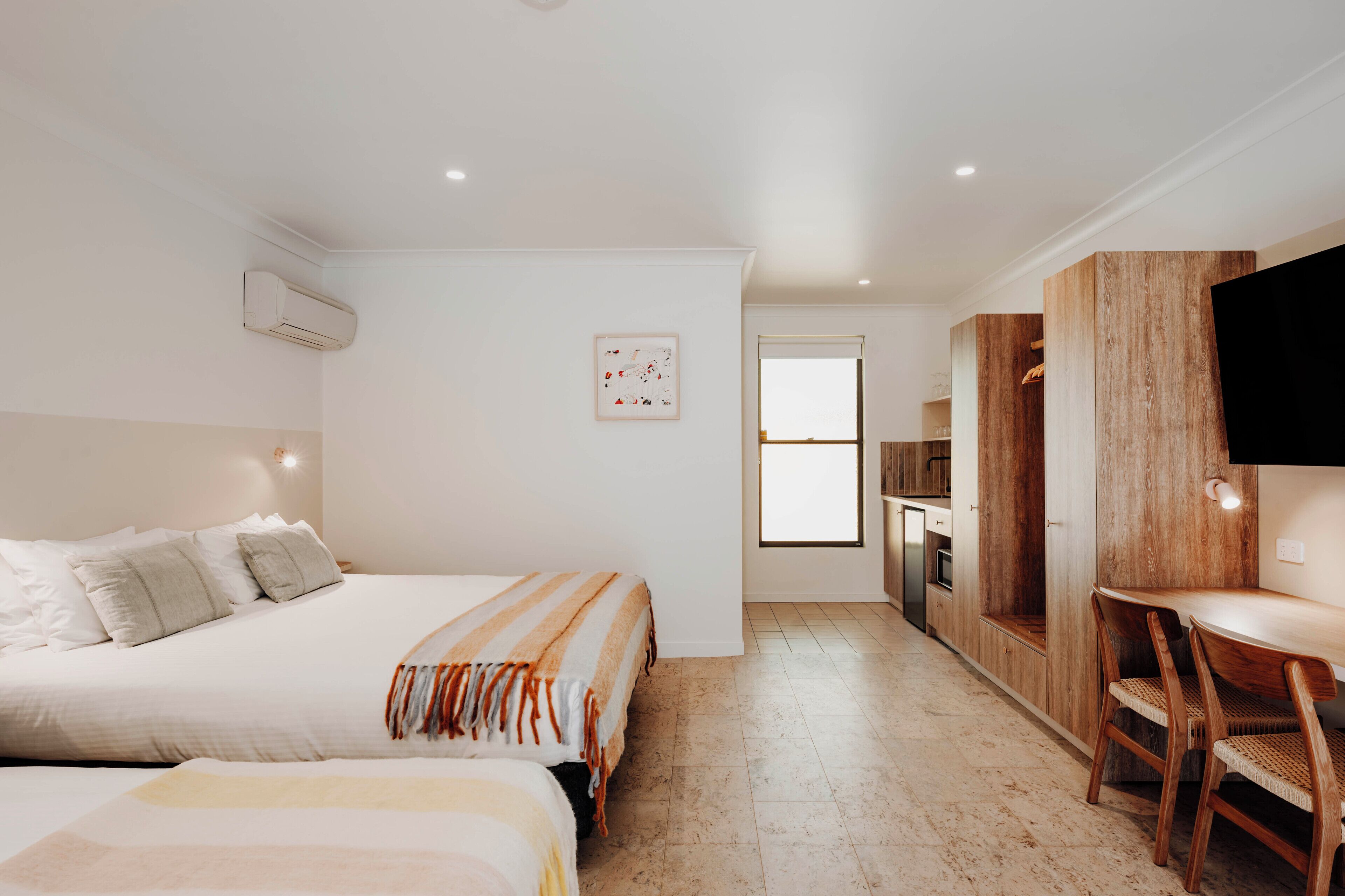 Una camera da letto moderna con un letto grande, un comodino, una piccola scrivania e una TV a parete.