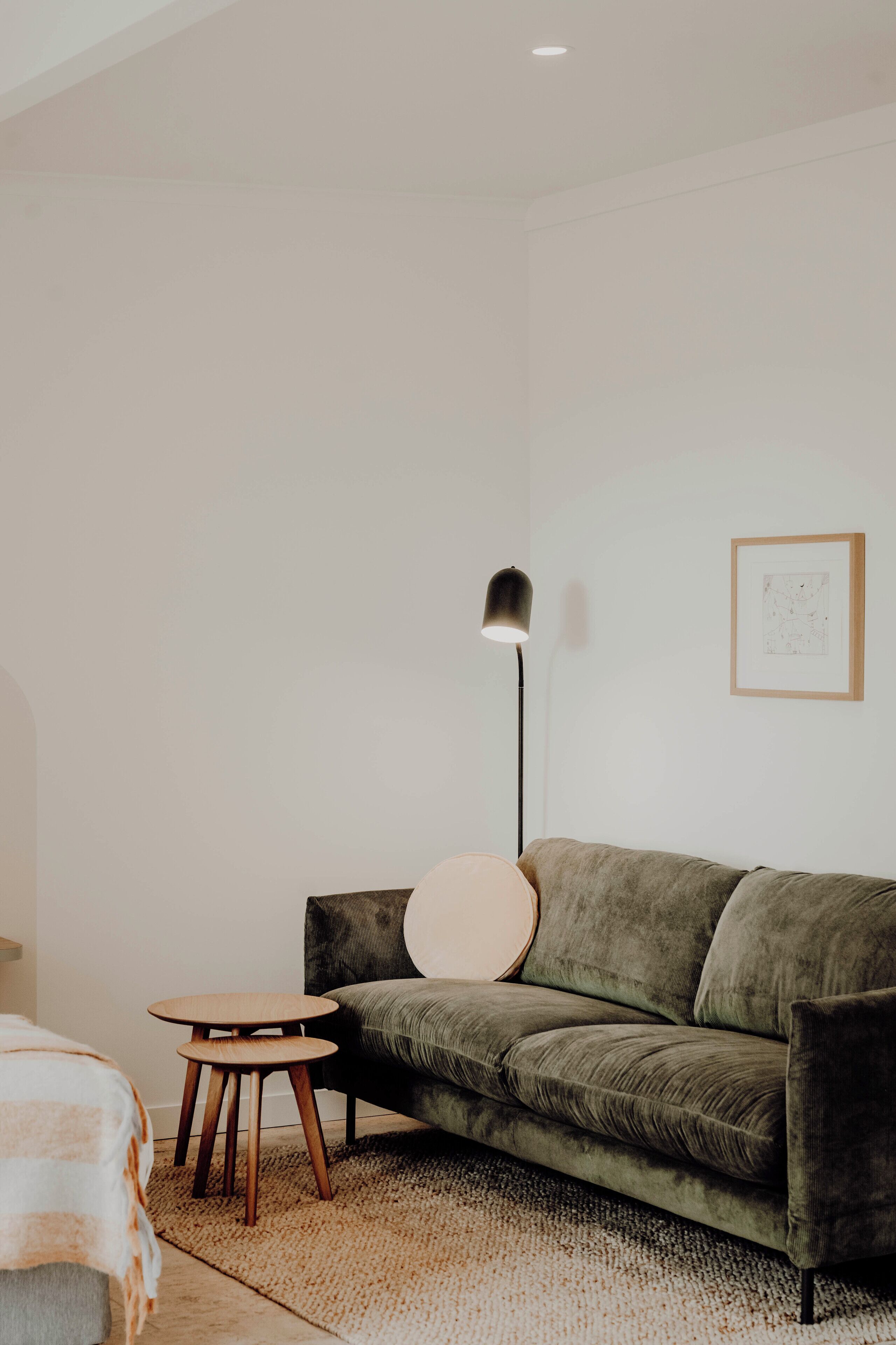 Ein stilvolles Wohnzimmer im minimalistischen Stil mit einem grünen Sofa, einem runden Couchtisch und einer Stehlampe.