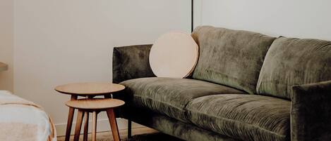 Ein stilvolles Wohnzimmer im minimalistischen Stil mit einem grünen Sofa, einem runden Couchtisch und einer Stehlampe.