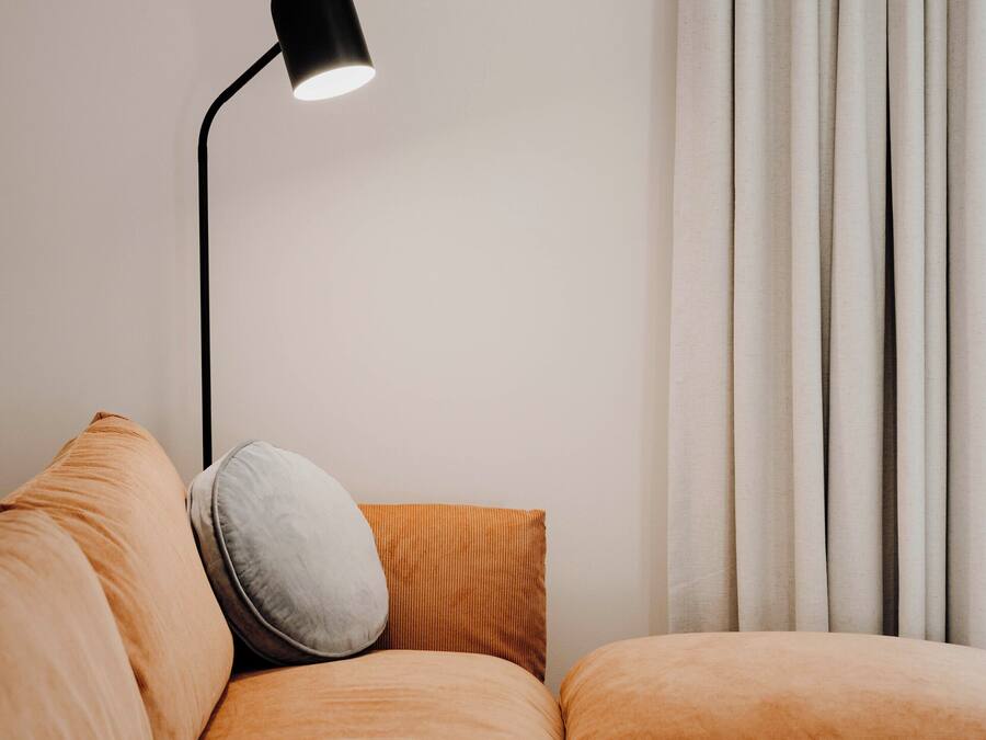 A modern living room with a sofa, a round wooden coffee table, and a floor lamp.