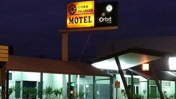 Ein Schild mit den Logos 'Cobb Inlander' und 'Orbit Inns', ein moderner Gebäudeeingang und Zimmerpflanzen.