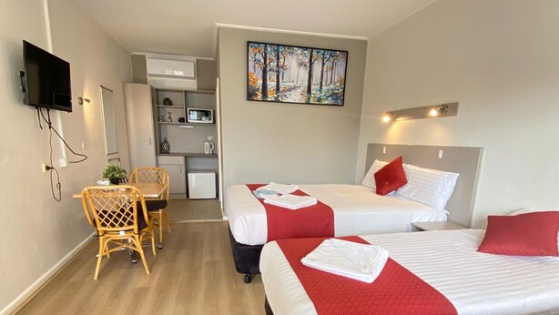 Une chambre d’hôtel avec deux lits, un bureau et une télévision.