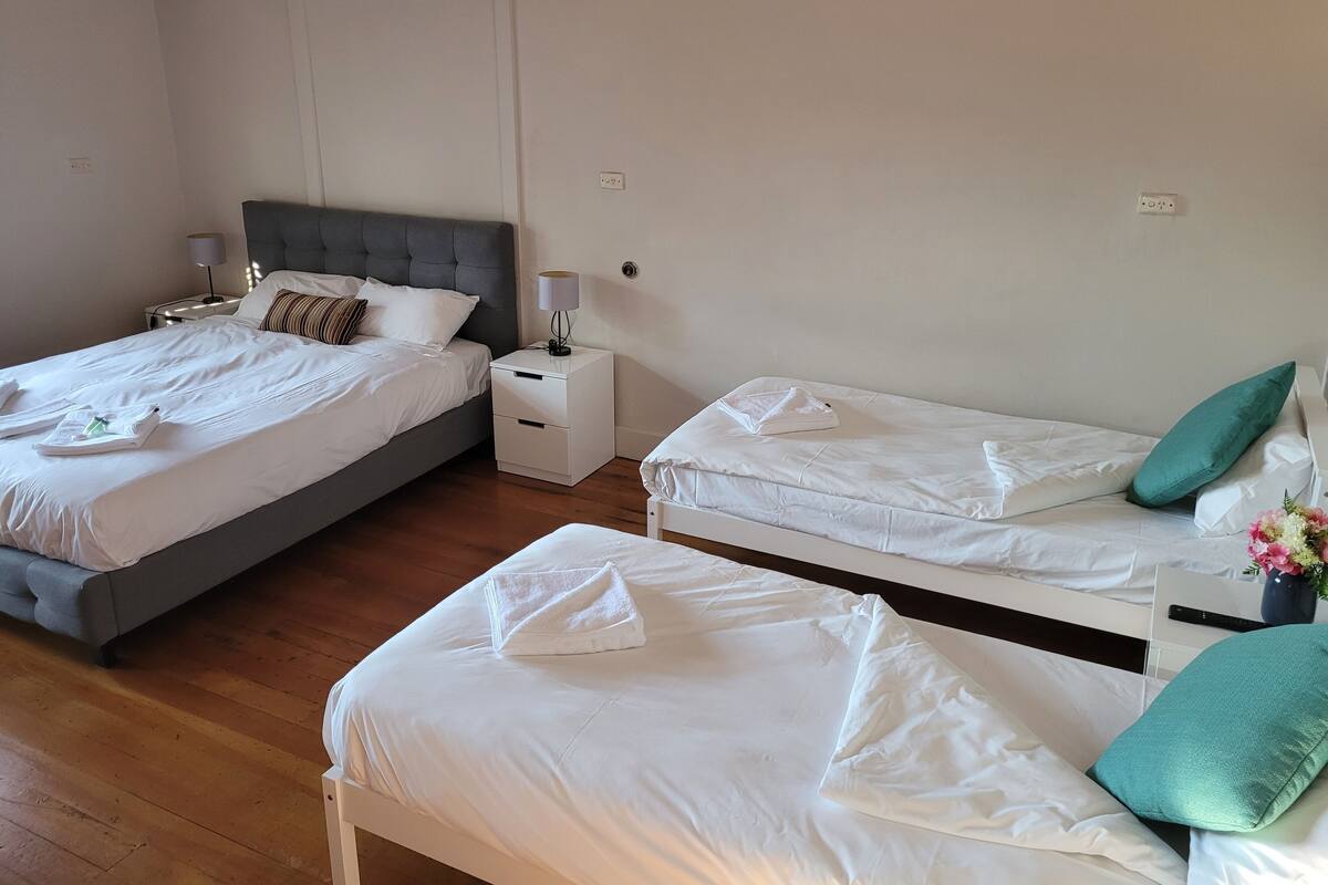 A hotel room with two beds, a nightstand with a lamp, and a wall-mounted air conditioner.