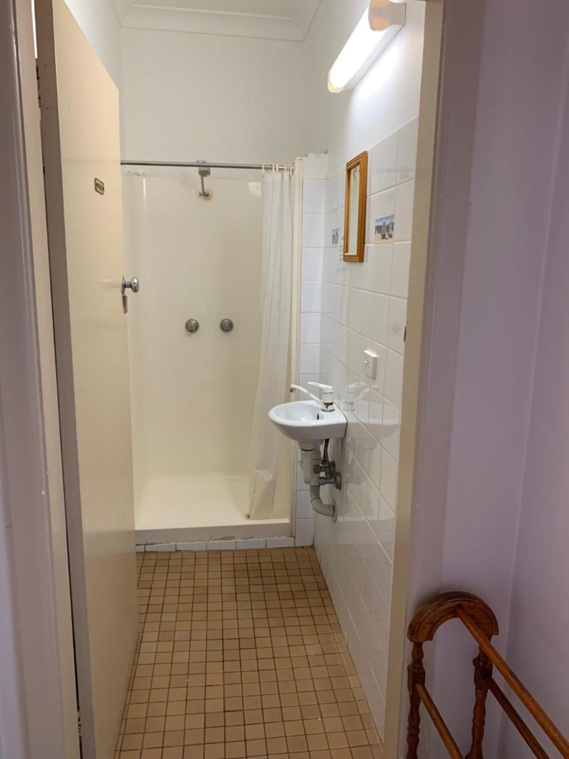 A small bathroom with a shower, a sink, and a mirror.