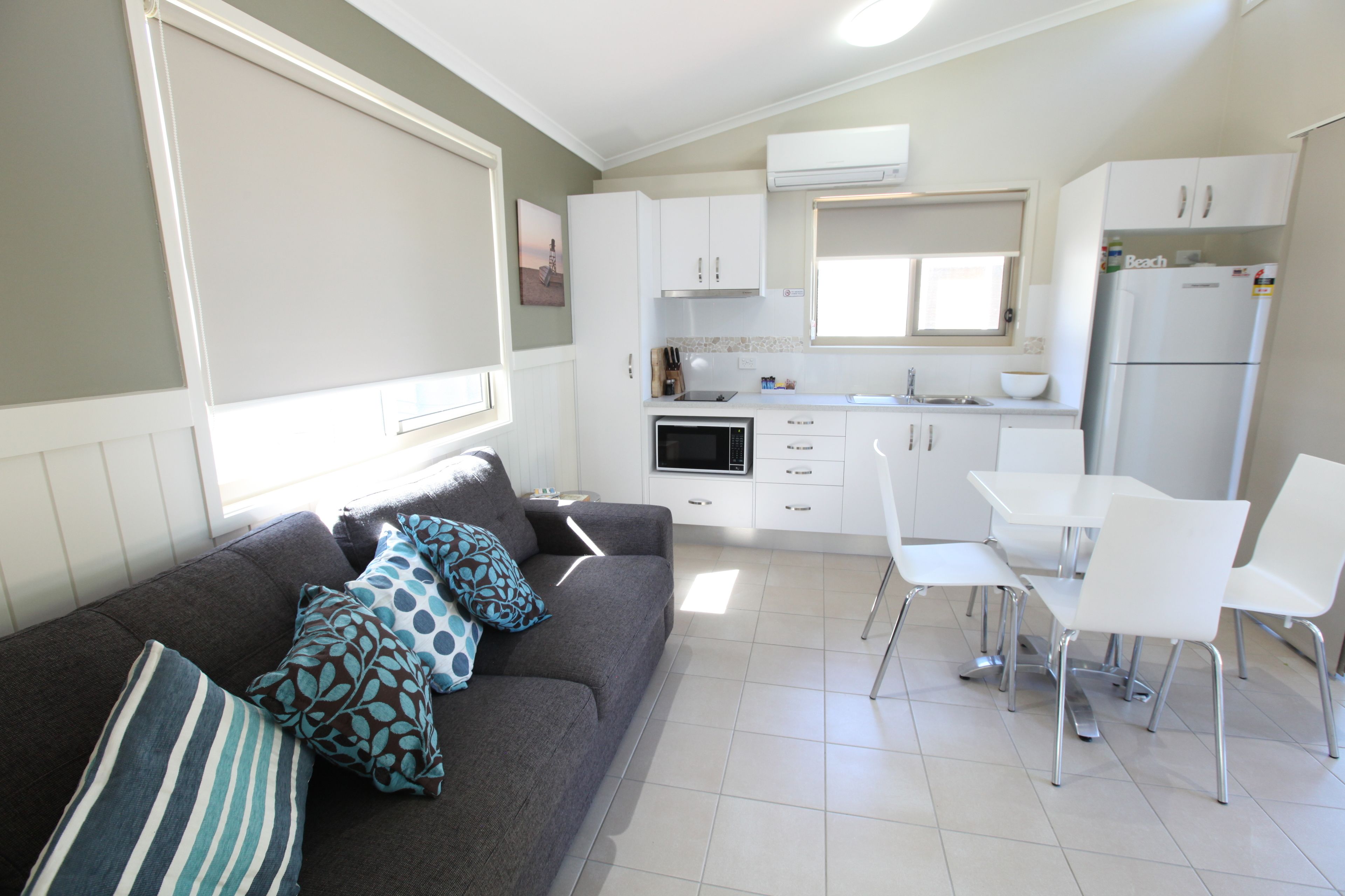 A compact living space with a sofa, dining table, chairs, and a kitchenette.