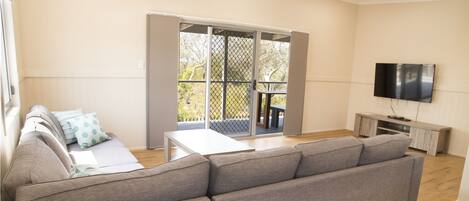 A modern living room with a grey sectional sofa, a white coffee table, and a TV mounted on the wall.