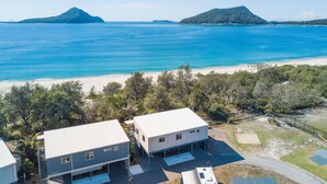 Una propiedad costera con dos casas independientes, una playa de arena y una vista despejada al mar.