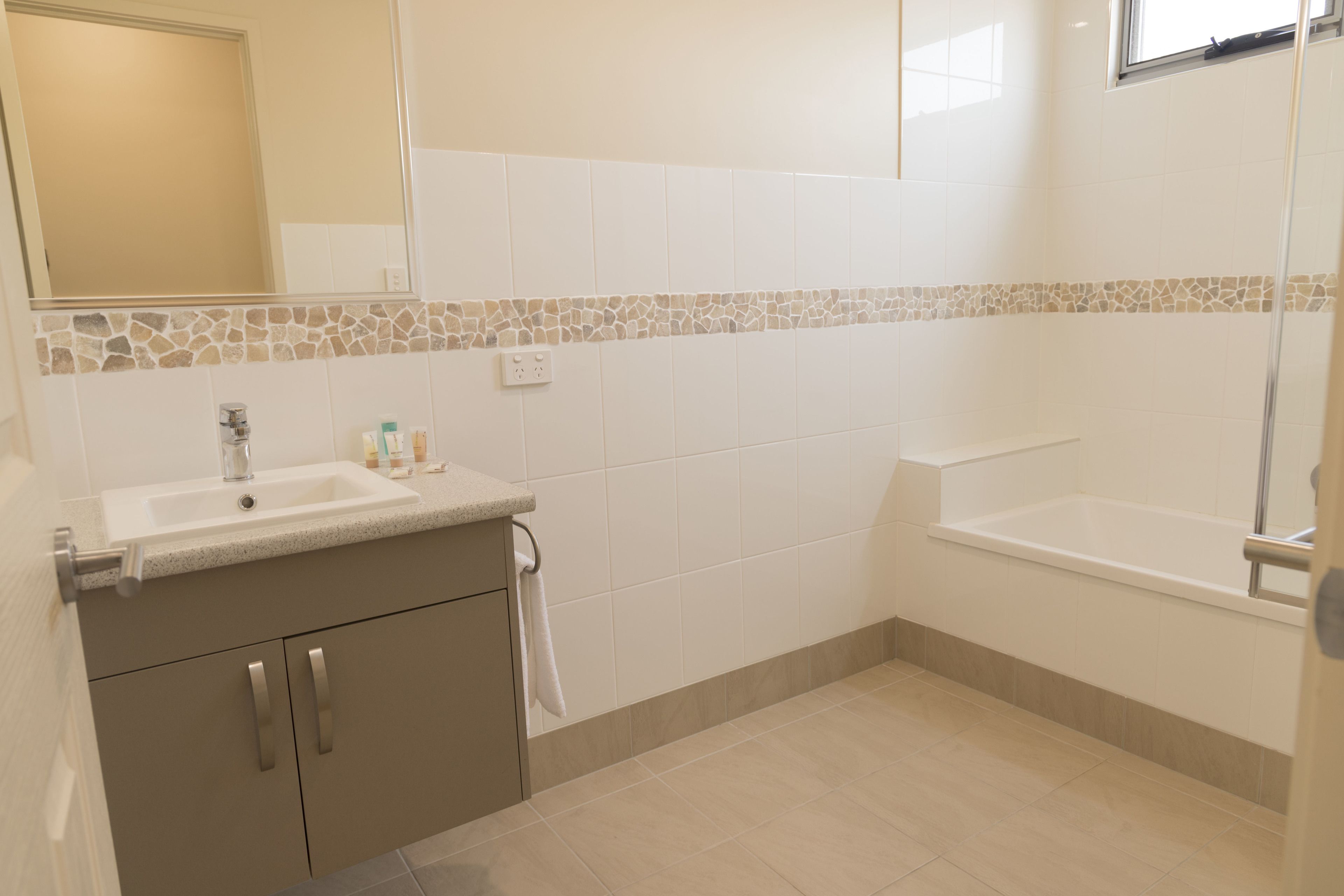 Une salle de bain avec un lavabo, un miroir et une baignoire.