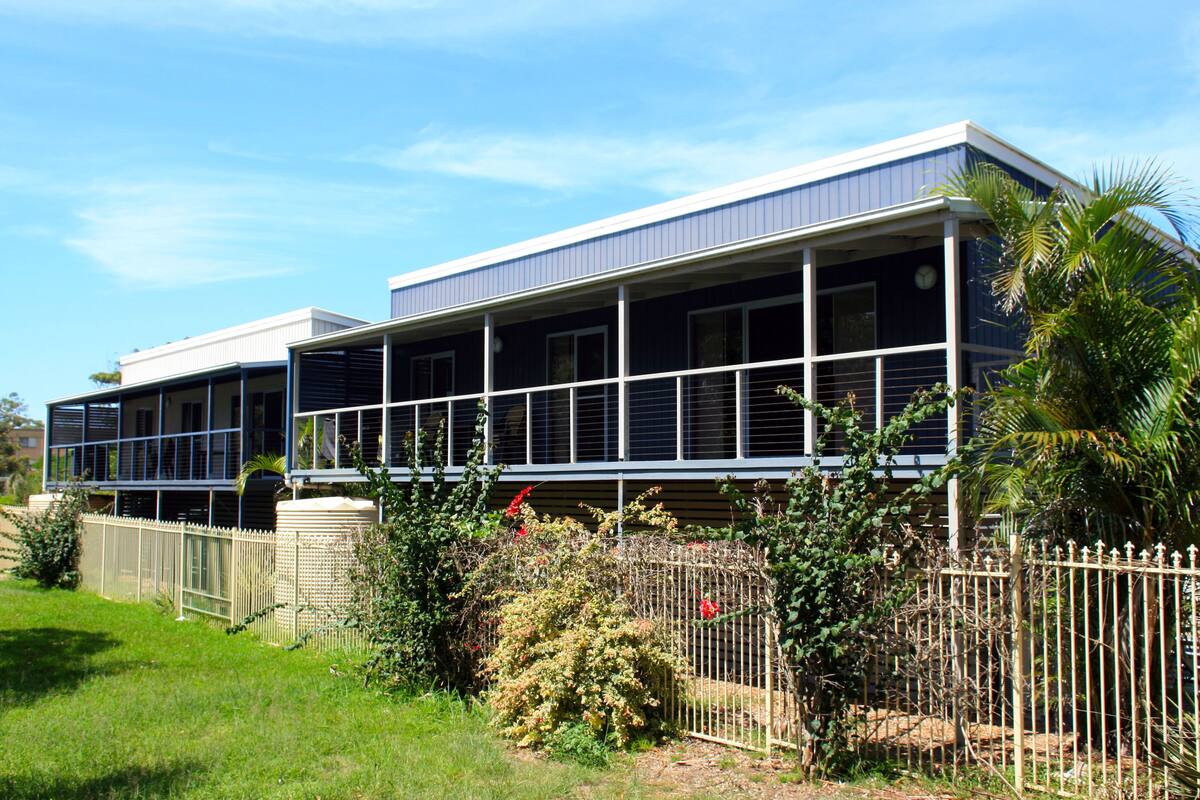 A two-story building with a flat roof and a balcony on the upper floor.
