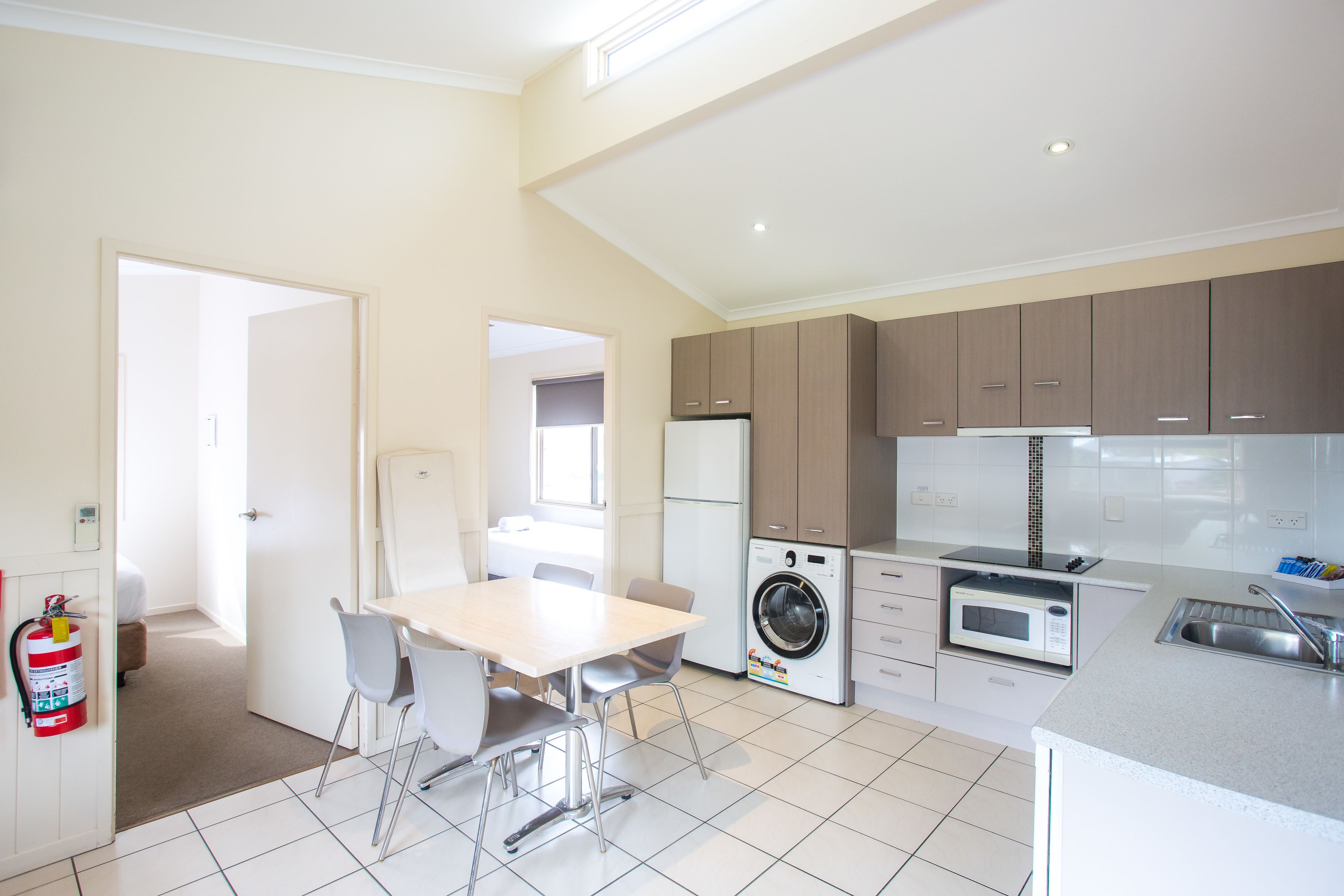 Une cuisine moderne équipée d’un lave-linge, d’un four à micro-ondes et d’un coin repas avec des chaises et une table.