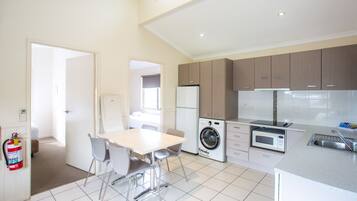 Une cuisine moderne équipée d’un lave-linge, d’un four à micro-ondes et d’un coin repas avec des chaises et une table.