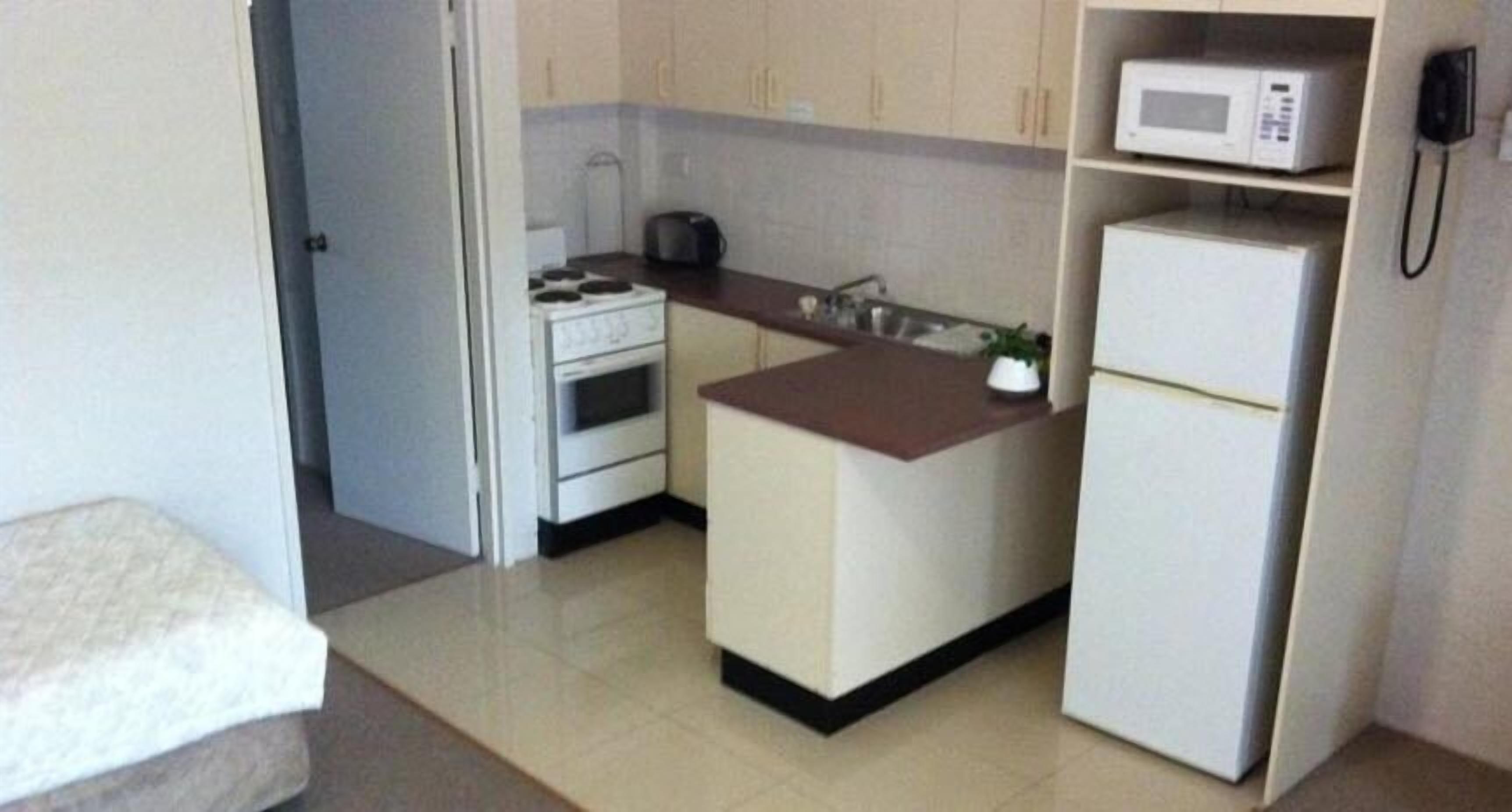A compact kitchen with a stove, microwave, and refrigerator.