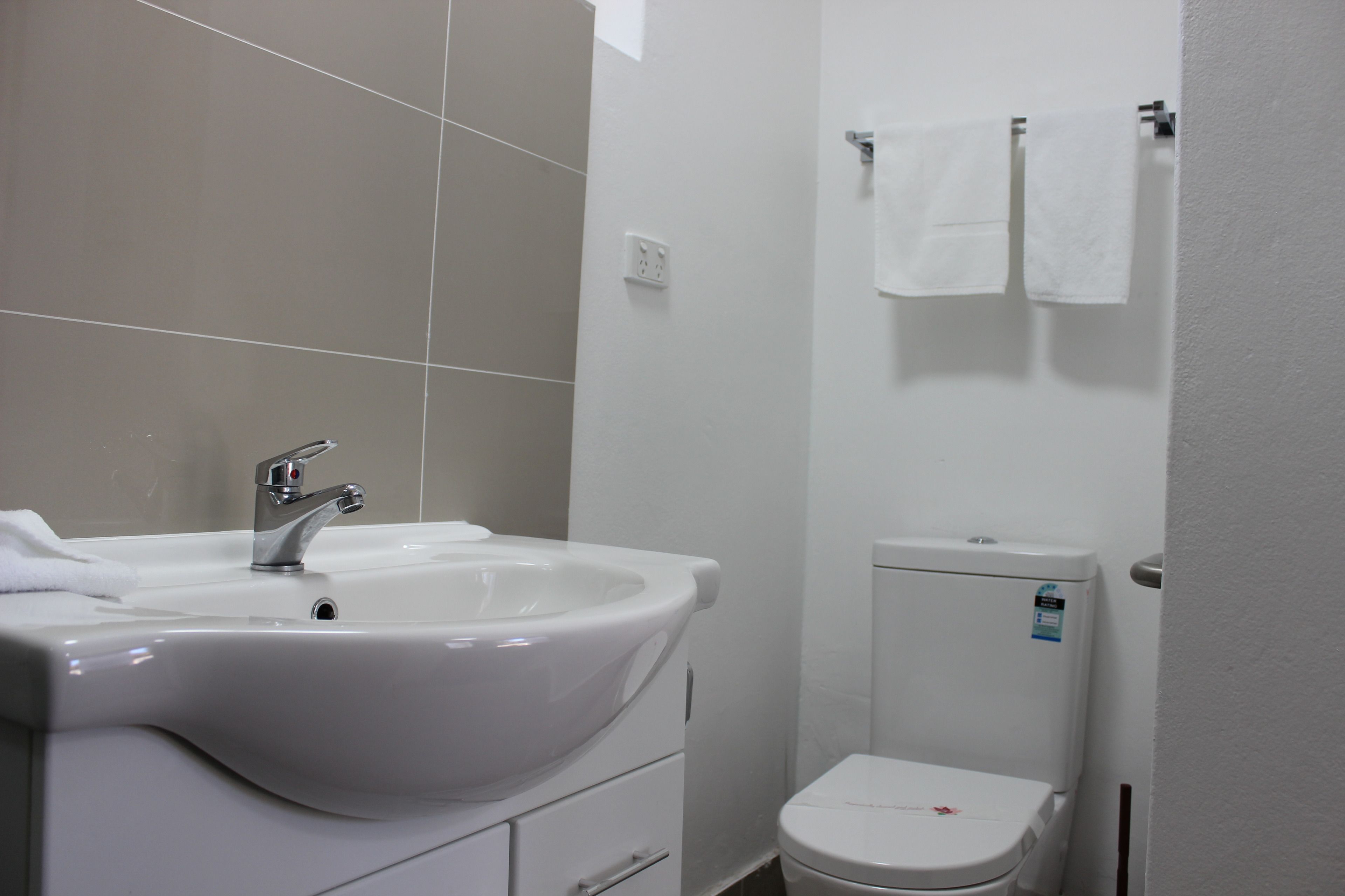 A bathroom with a white sink, faucet, and toilet.