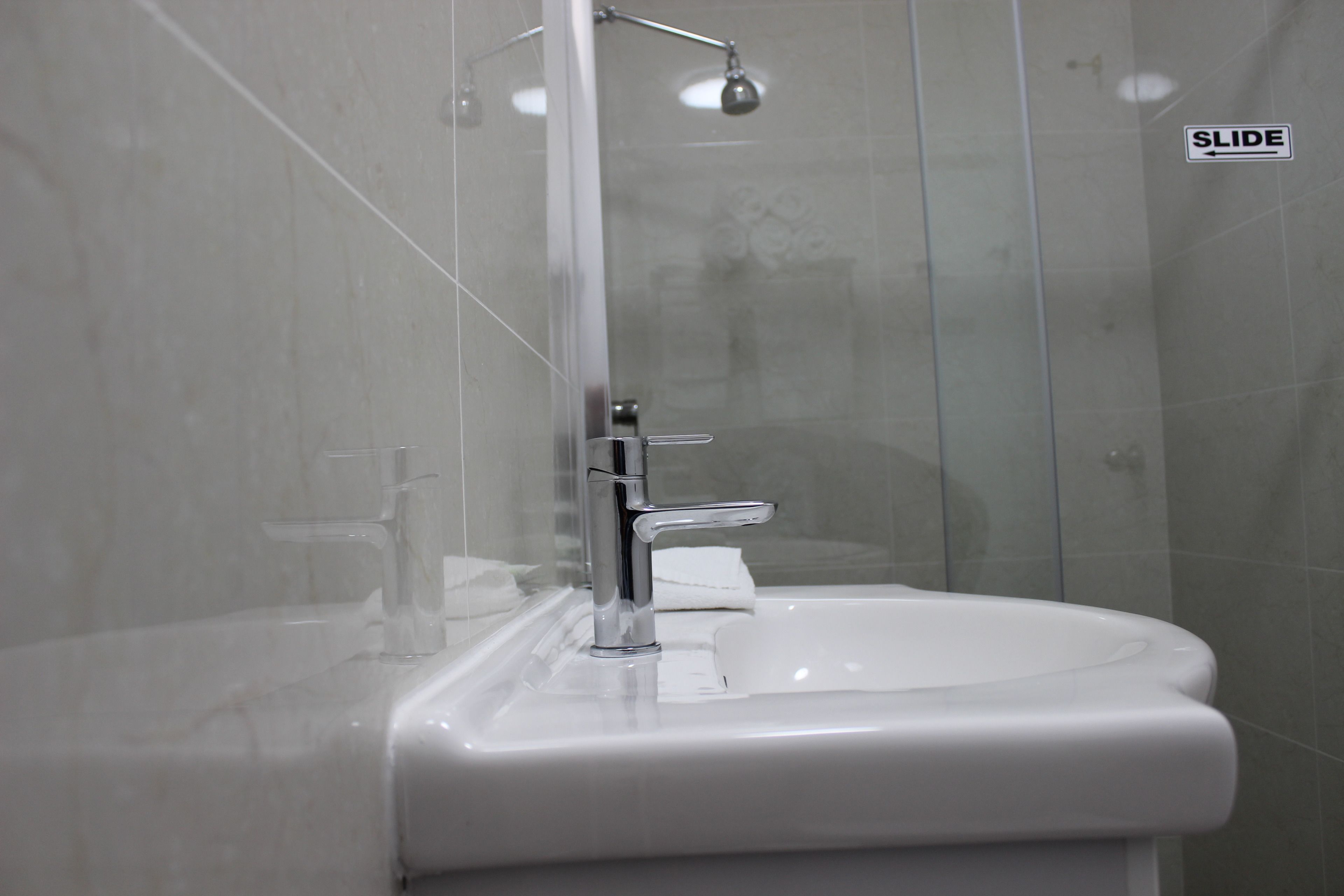 A bathroom with a white sink, a chrome faucet, and a glass shower enclosure.