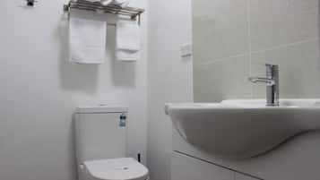 A bathroom with a toilet, a sink, and a towel rack with neatly rolled towels.