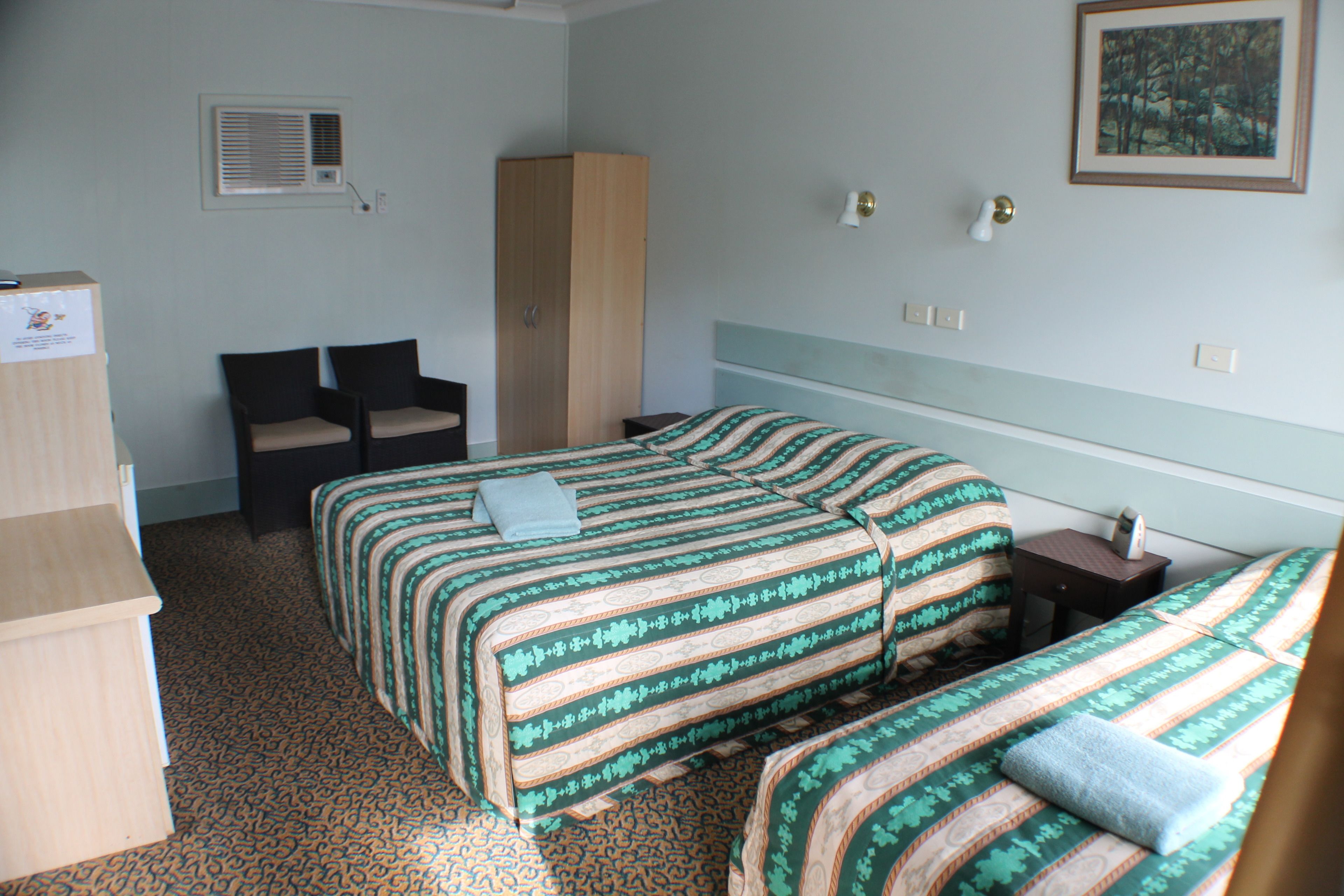 Une chambre d’hôtel avec deux lits, une armoire, un bureau et une chaise.