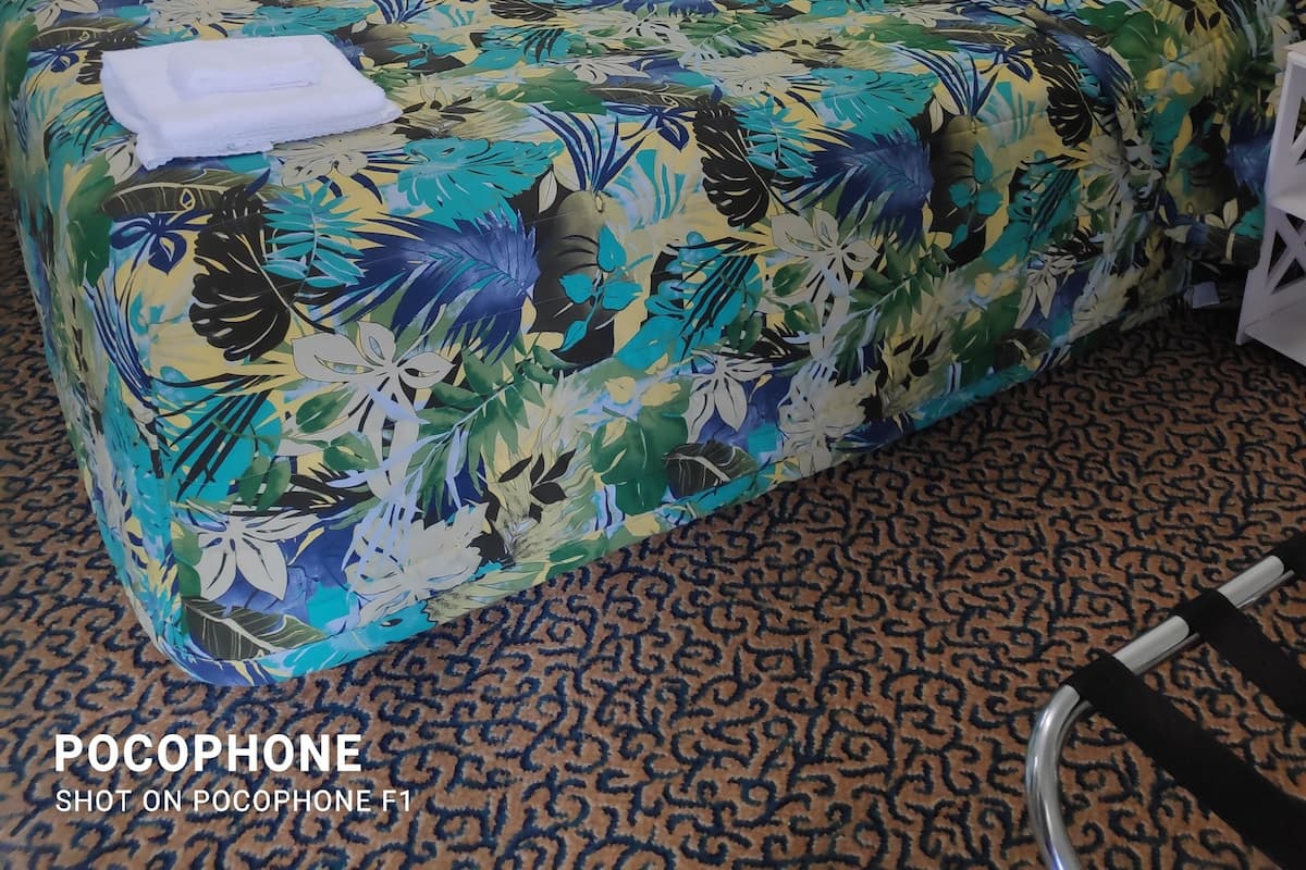 A hotel room with a bed, a chair, a nightstand, and a window with curtains.