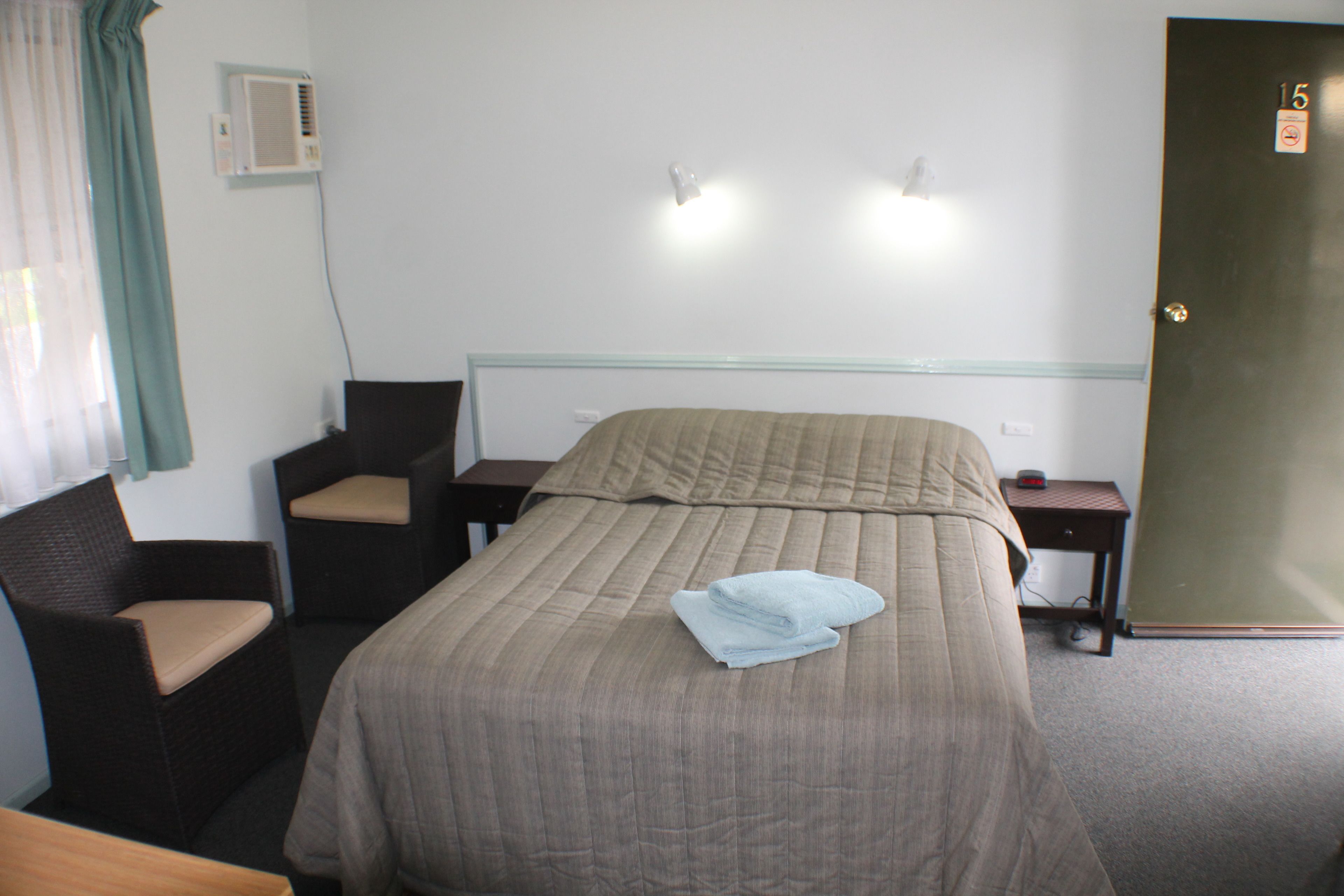 Una habitación de hotel con una cama, dos sillas, un escritorio y una puerta.