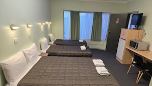 Ein Hotelzimmer mit zwei Betten, einem Schreibtisch, einer Mikrowelle, einem Fernseher und einem kleinen Kühlschrank.