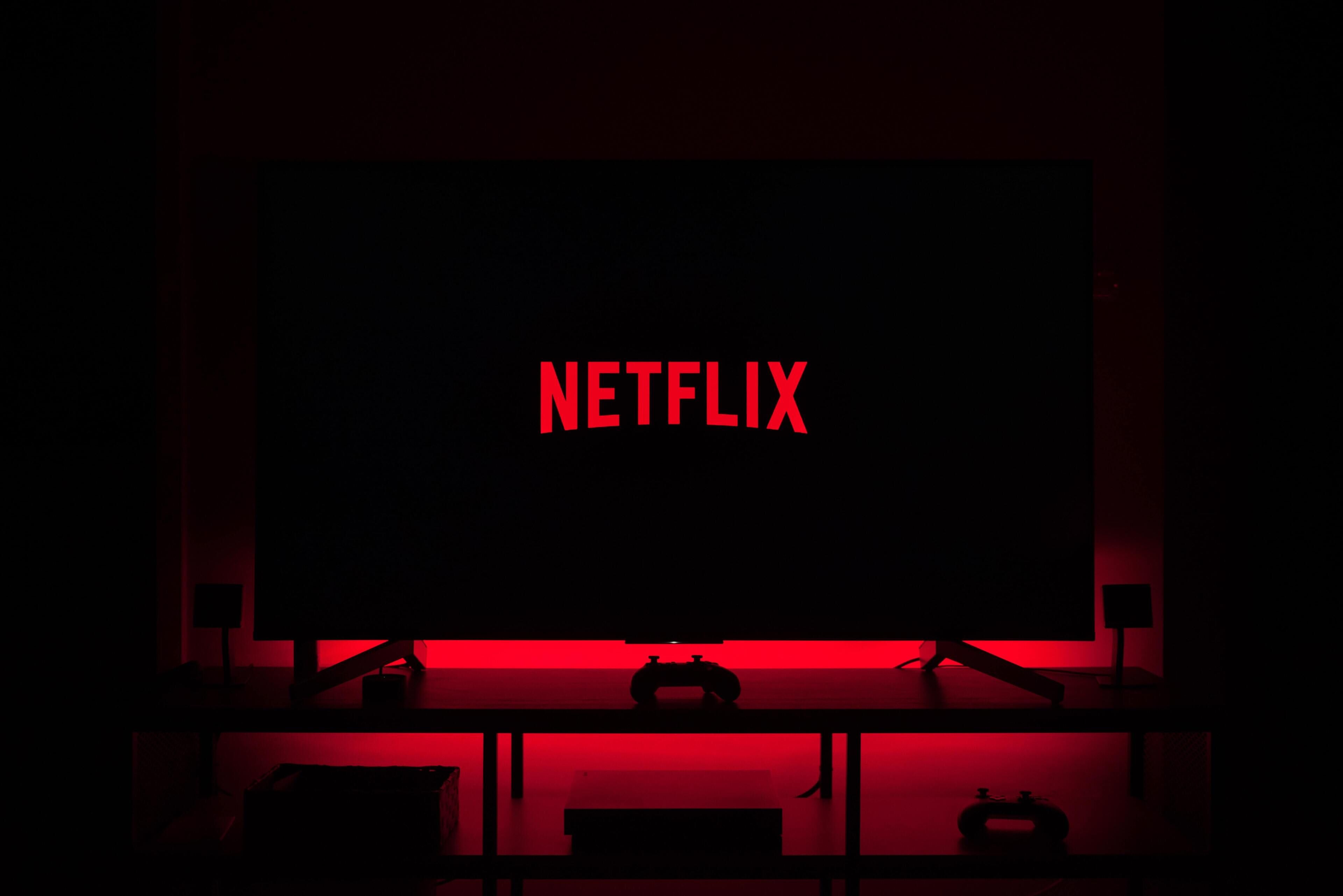 Una habitación oscura con una pantalla iluminada en rojo mostrando el logotipo de Netflix.