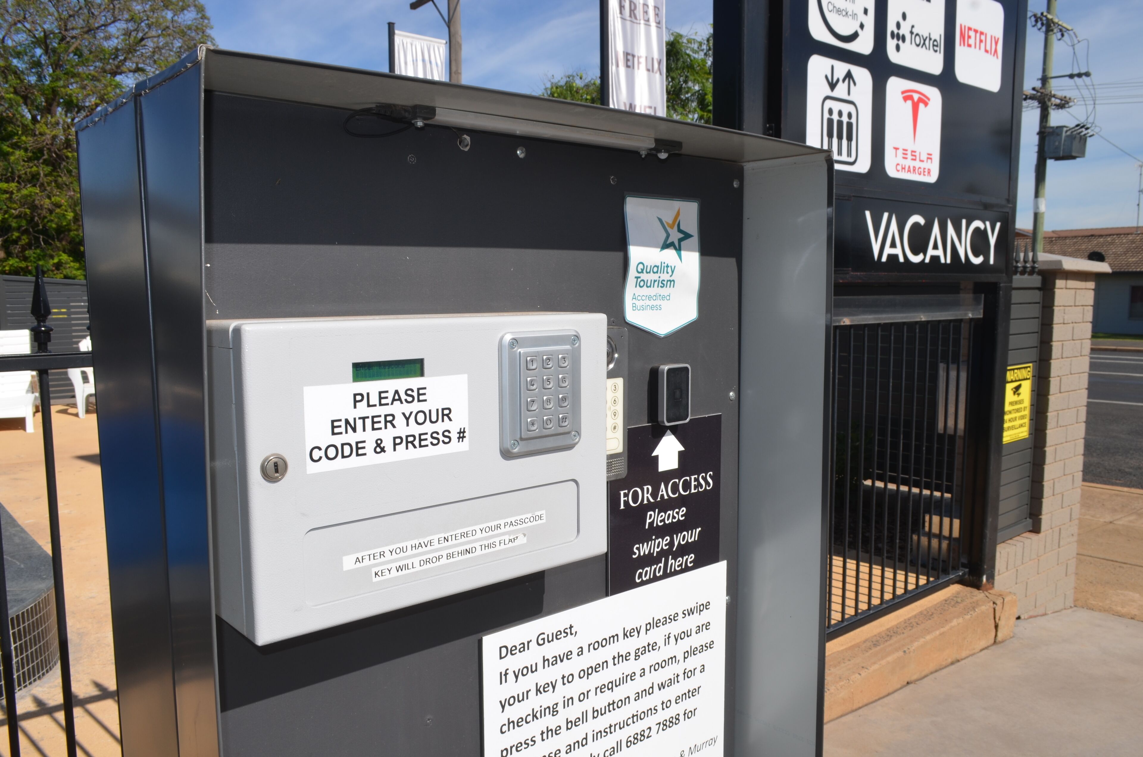 A security kiosk with a keypad and a sign instructing to enter a code and press a button.