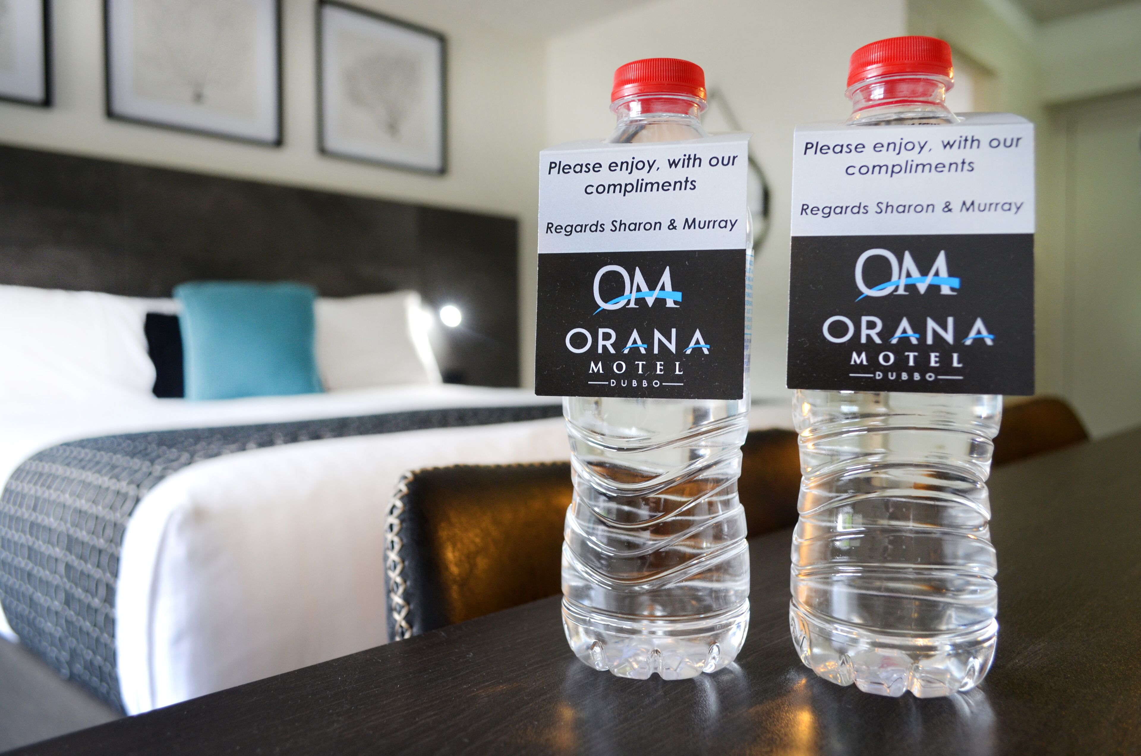 Two bottles of water with labels on a table in a hotel room.