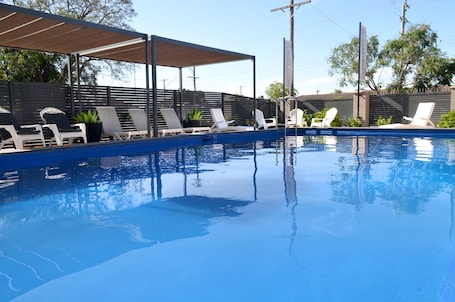 Una piscina al aire libre, sillones reclinables de piscina