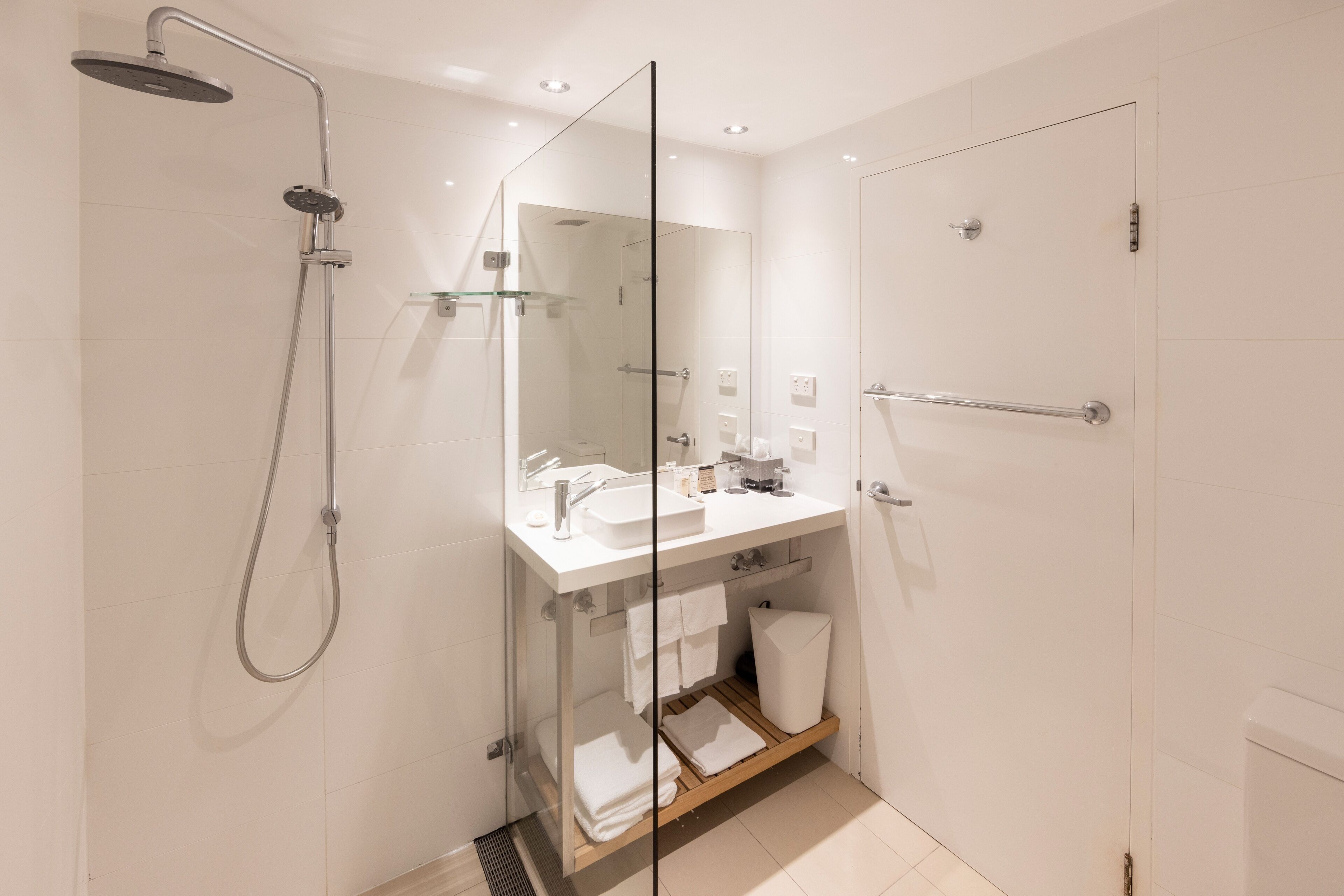 A modern bathroom with a glass shower enclosure, a white sink, and a glass door.