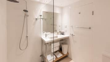 A modern bathroom with a glass shower enclosure, a white sink, and a glass door.