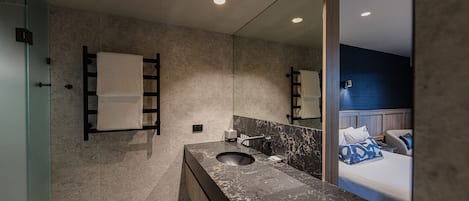 Un baño moderno con un espejo grande, un lavamanos y un perchero para toallas.