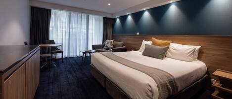 Une chambre d’hôtel avec un grand lit, un bureau et une chaise.