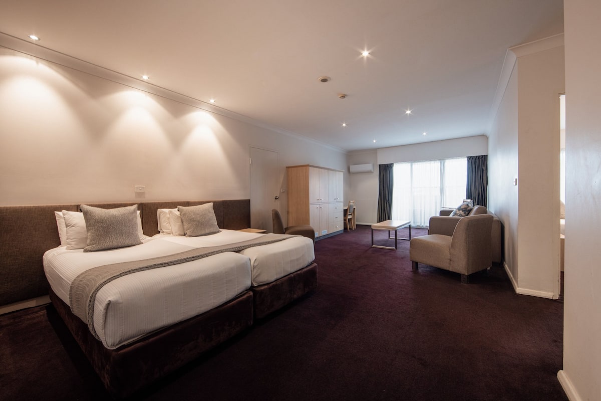 A hotel room with a large bed, a desk, and a chair.
