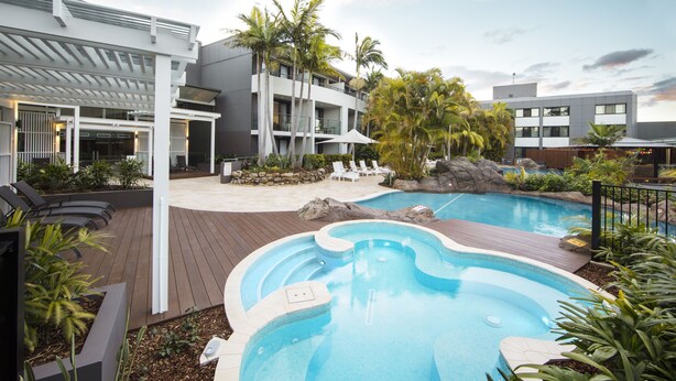 A modern hotel with a pool area, including a hot tub and lounge chairs. - The Executive Inn (New Lambton)