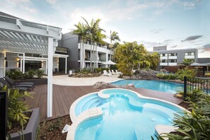 A modern hotel with a pool area, including a hot tub and lounge chairs. - The Executive Inn (New Lambton)