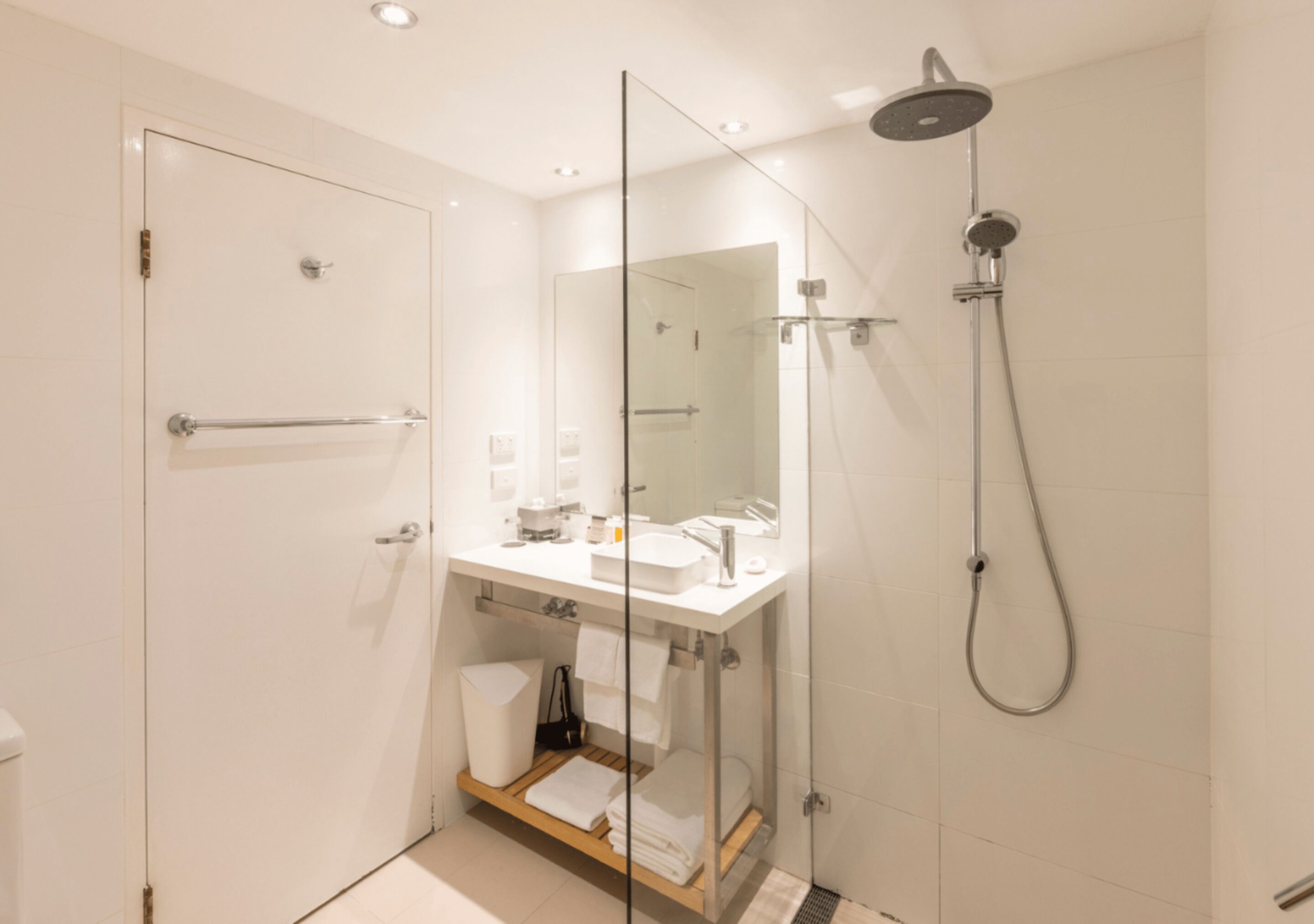A modern bathroom with a glass shower enclosure, a white sink, and a vanity with a mirror.