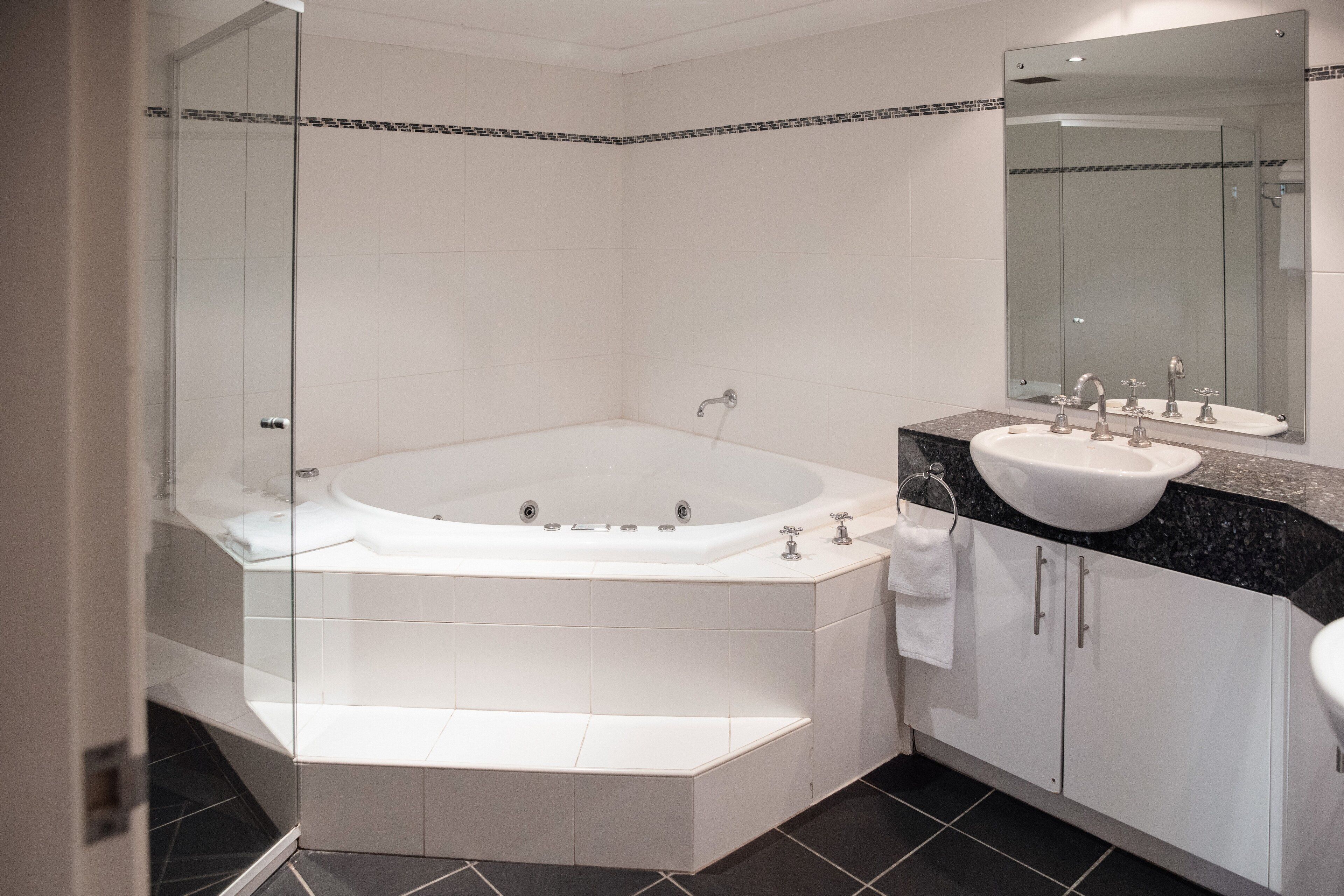 A modern bathroom with a freestanding bathtub, a vanity with a sink, and a large mirror.