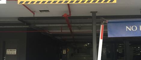 A parking garage entrance with a maximum head clearance sign of 2.150m, a fire smoke door warning, a speed limit sign of 15, and a sign indicating the Executive Inn is for hotel guests only.