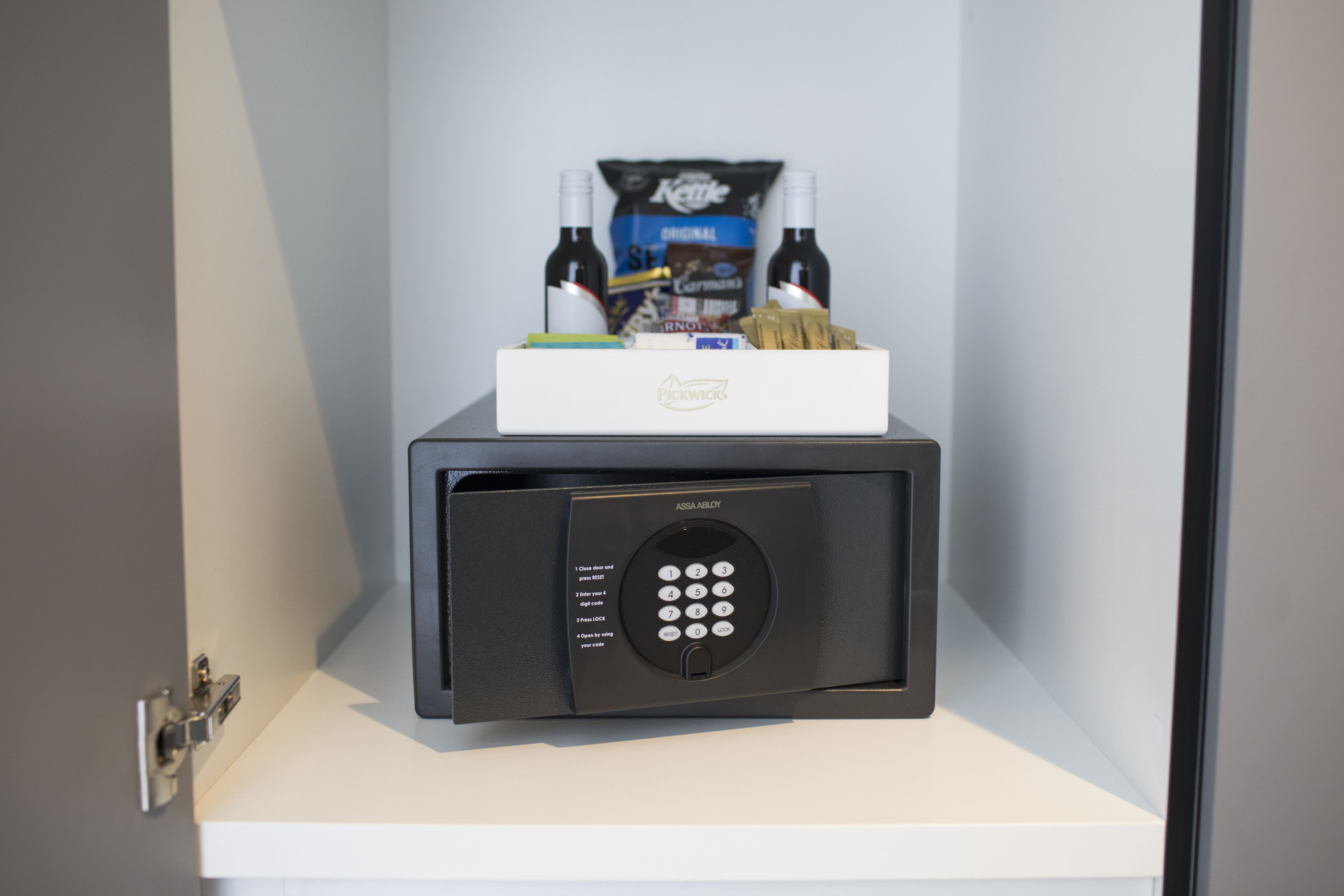A minibar with a secure lock, a bottle of wine, a pack of cigarettes, and a box of tissues.