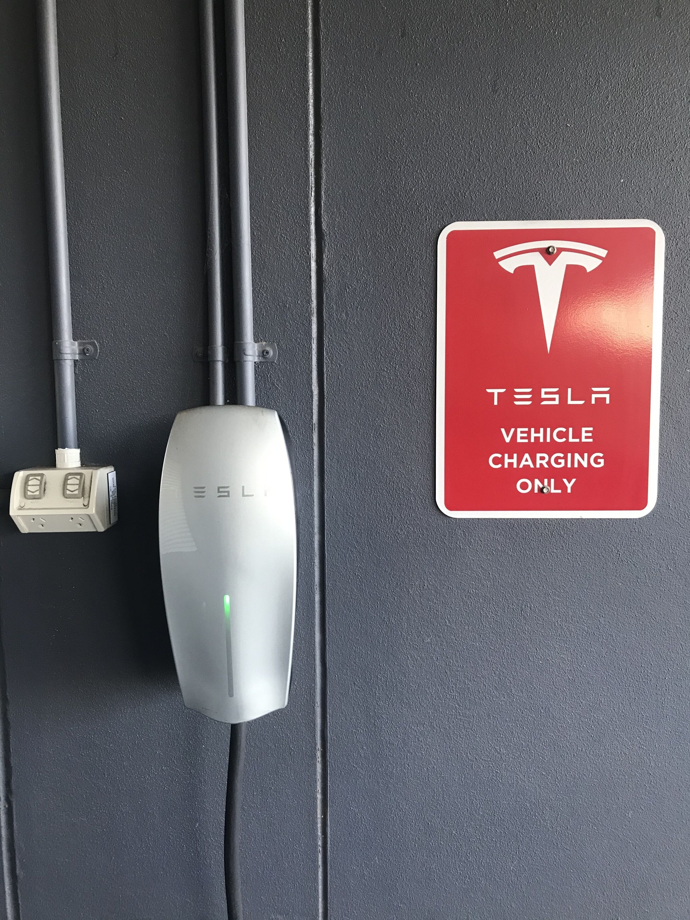 A Tesla vehicle charging station with a sign indicating it is for Tesla vehicle charging only.