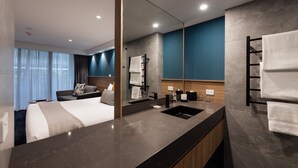 A modern hotel bathroom with a large mirror, a sink, and a towel rack. - The Executive Inn (New Lambton)