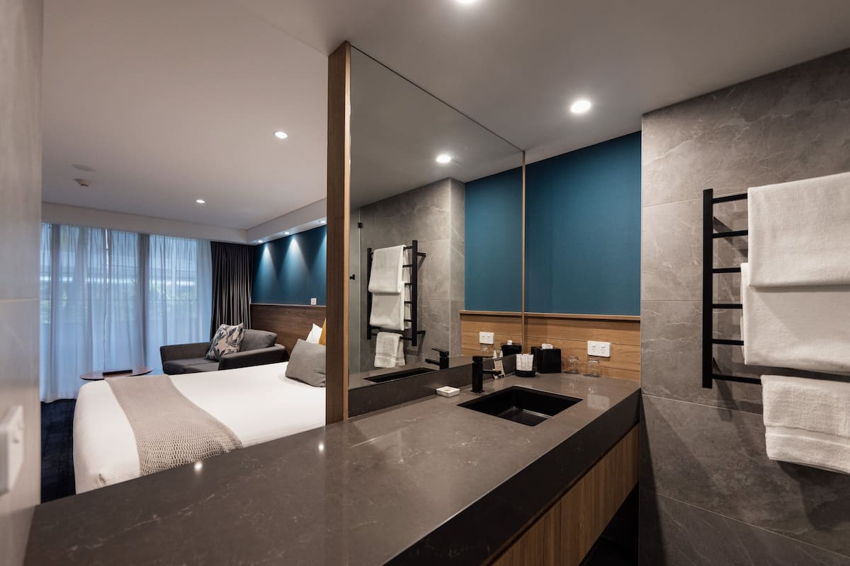 A modern hotel bathroom with a large mirror, a sink, and a towel rack.