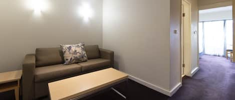 A modern living room with a sofa, a small table, and a door leading to another room.