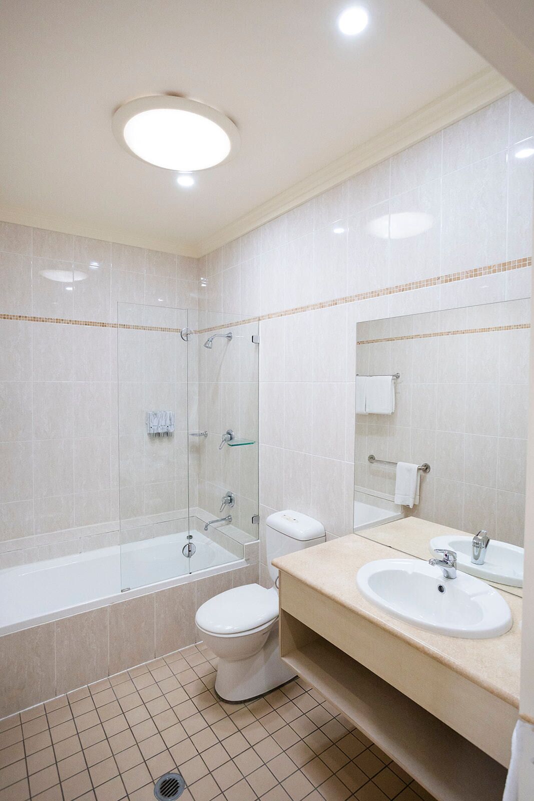 Un baño moderno con ducha envuelta en vidrio, inodoro, lavamanos y espejo.