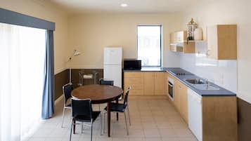 A compact kitchen with a dining area, a refrigerator, a microwave, and a sink.