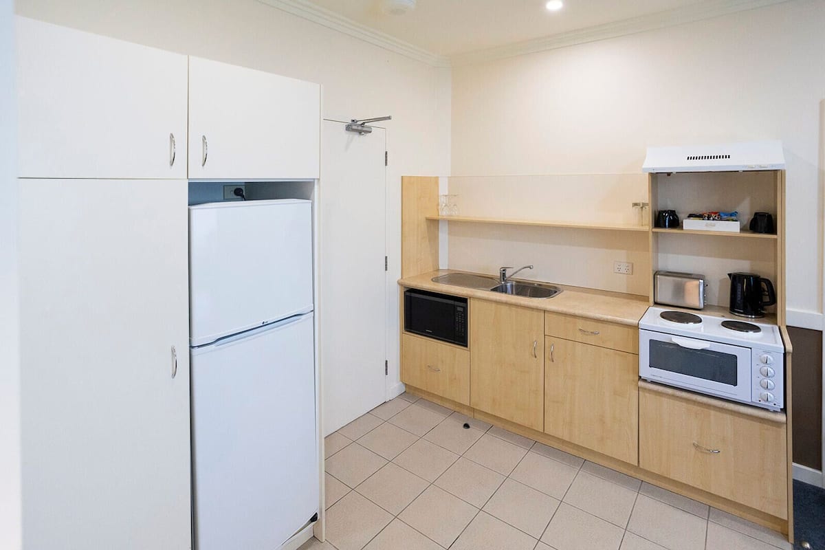 A compact kitchen with a refrigerator, microwave, toaster, and sink.