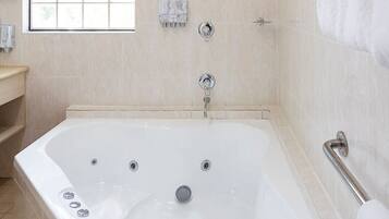 A modern bathroom with a large bathtub, a window, and a towel rack.
