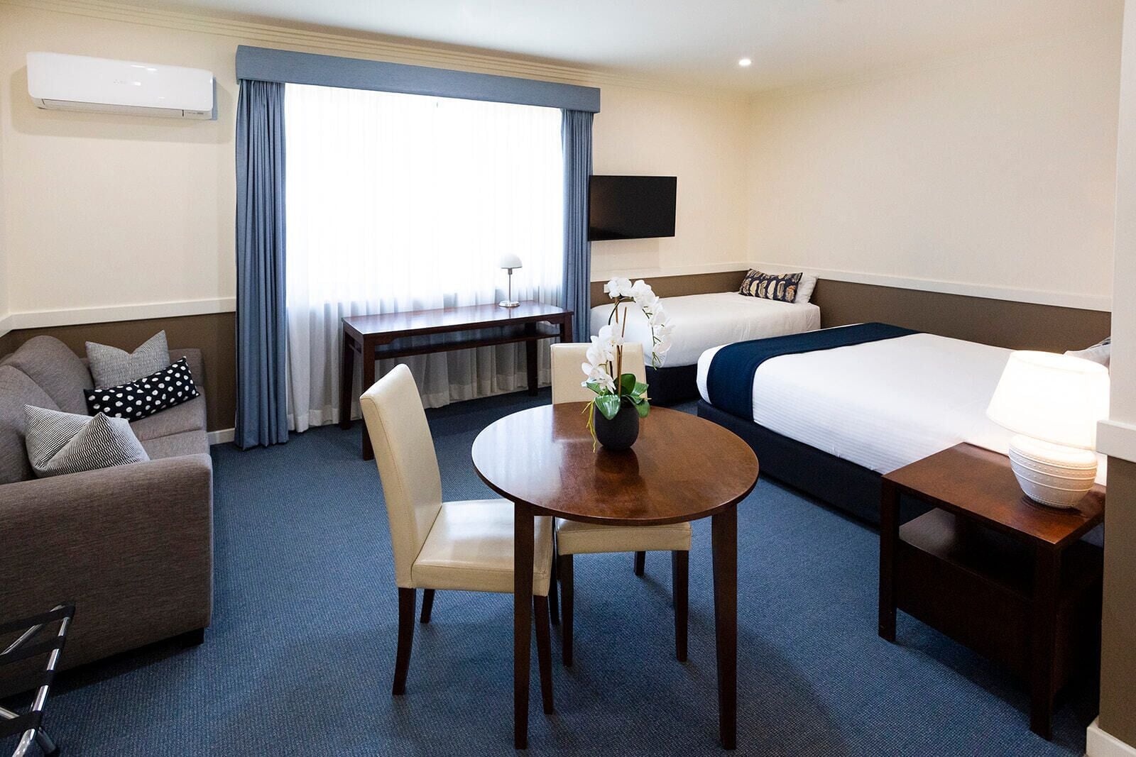 Una habitación de hotel con cama, escritorio, sofá, mesa y televisión.