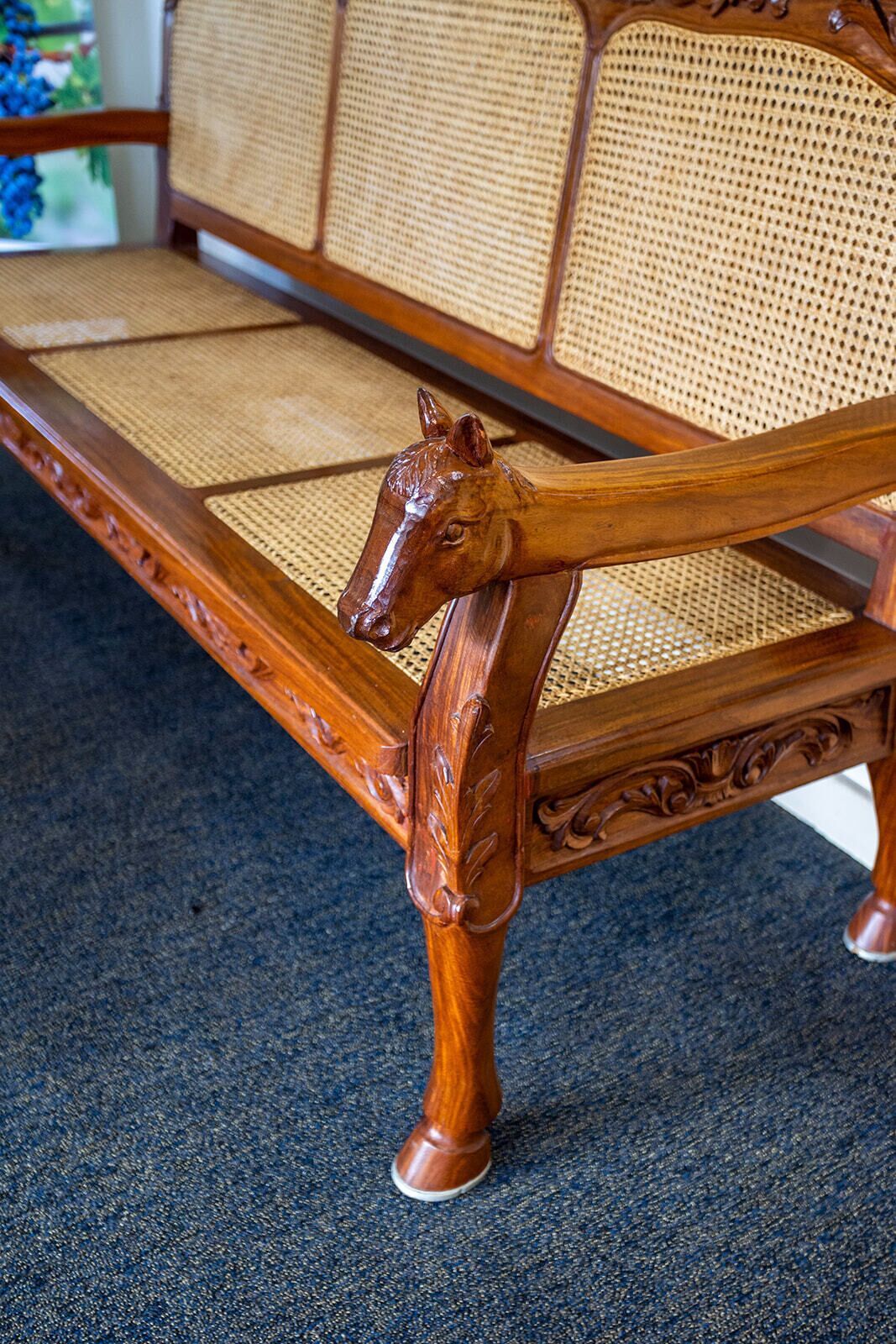 A wooden bench with a horse head carved into the backrest.