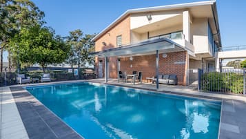 Una piscina al aire libre, sillones reclinables de piscina